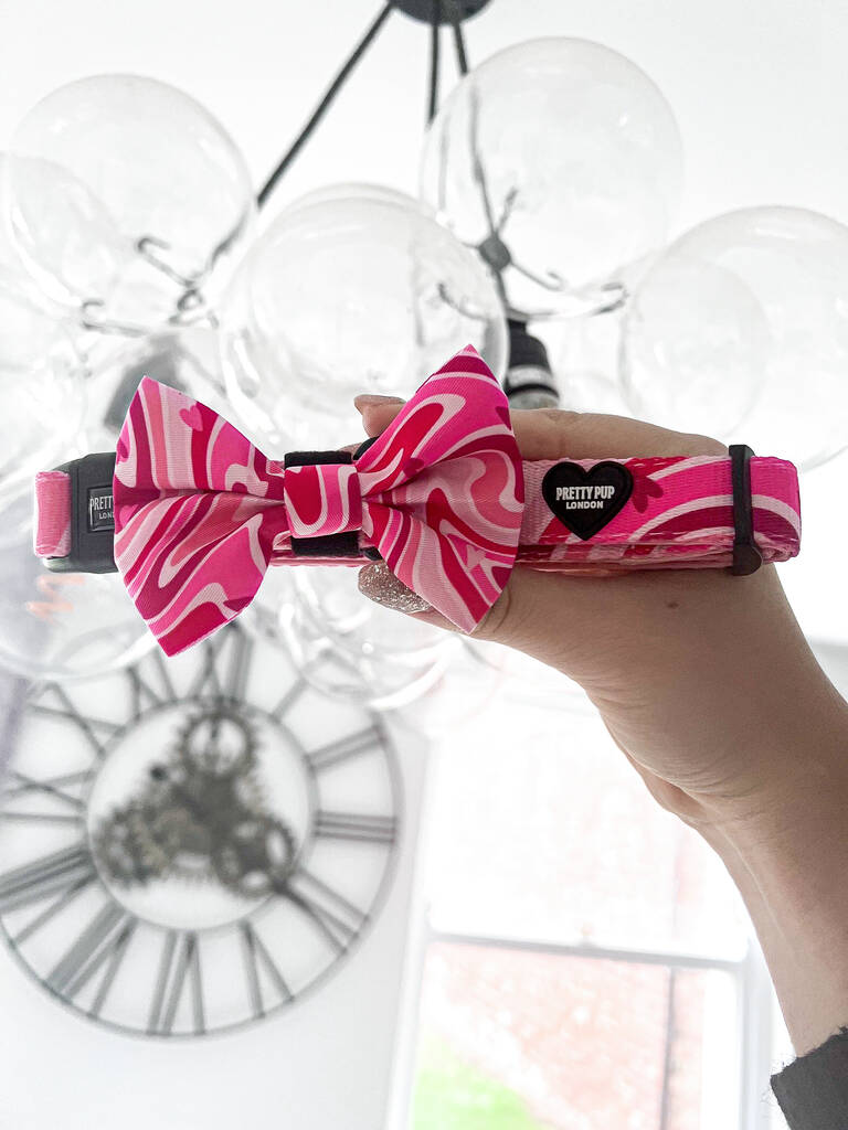 pink dog bow attached to a pink adjustable dog collar being held up for a photo