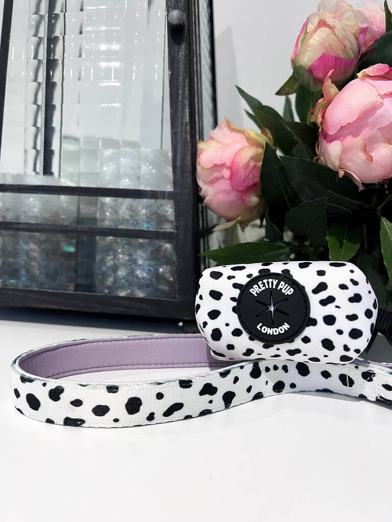 purple designer dog lead laid out on surface with dalmatian print dog poo bag holder attached 