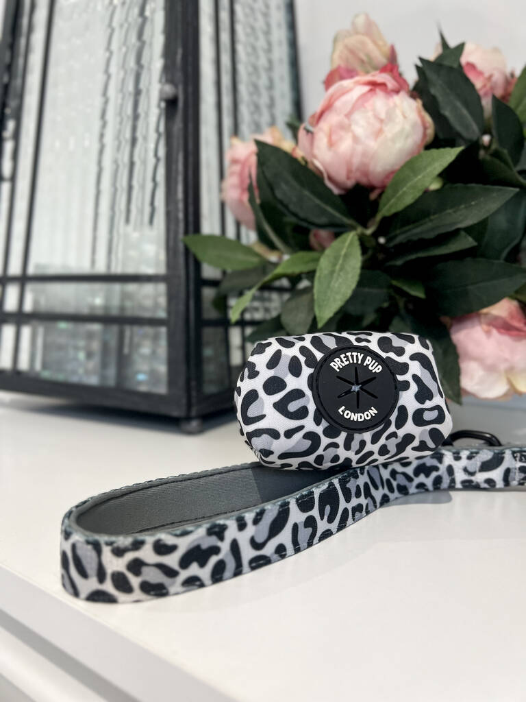 grey leopard print dog poo bag holder and handle of matching dog lead lay on a countertop