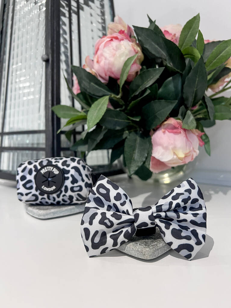 matching leopard print dog bow tie and leopard print dog poo bag dispenser next to each other